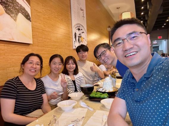 Lab members pose for group photo around table in restaurant