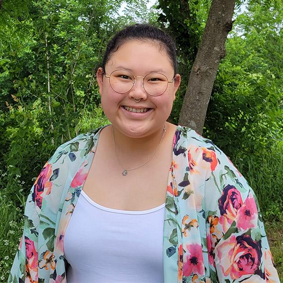 Woman in woods wearing white shirt and flower print top