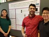 Four lab members pose for the camera in front of poster presentation