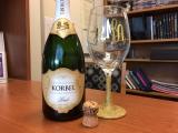 Bottle of champaign, cork and initialed wine glass sitting on a table
