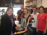 Five team members standing at table with cake and champaign