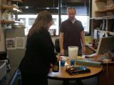 Two team members standing at table with cake and champaign
