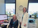 two women, one seated, in an office setting.