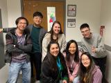 Dr. Dan Tong with six lab members gathered in front of a doorway